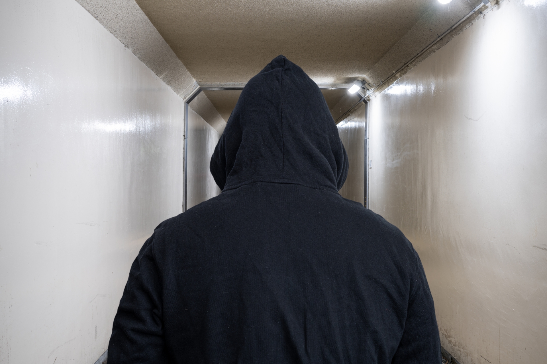 フードを被った怪しい人物の後ろ姿