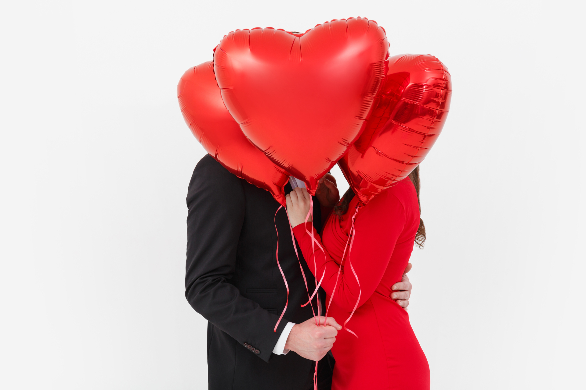 ３個のハート型の風船で顔を隠すカップル