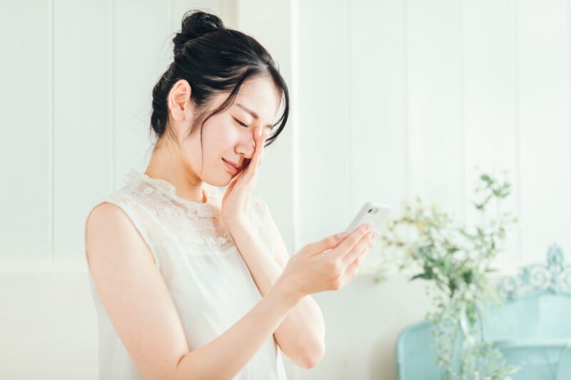 スマホを見て悩む女性