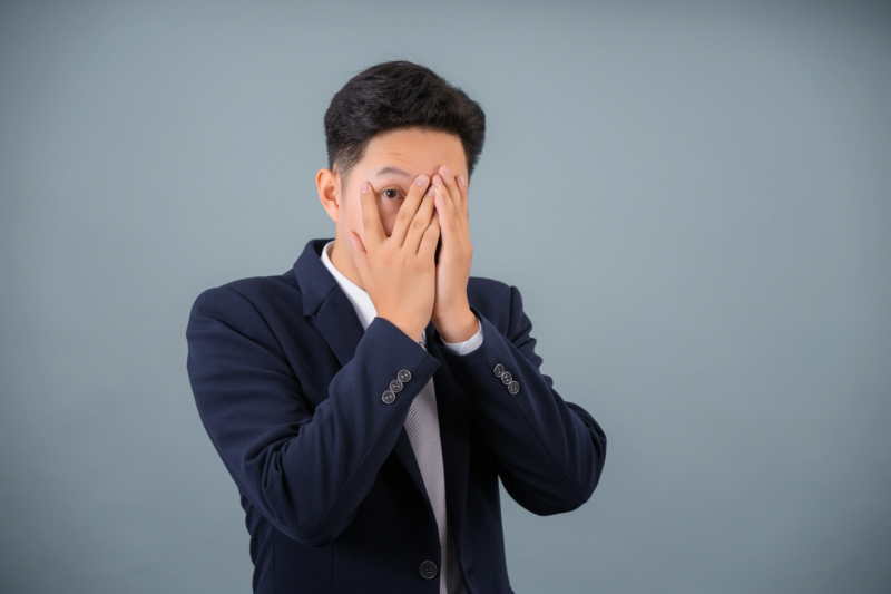 指の間からこちらを見る韓国人男性