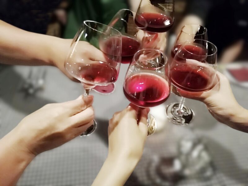 ワイングラスを持って乾杯する複数男女の手