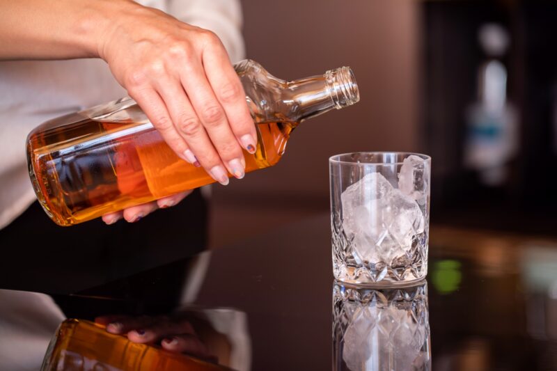 グラスにウィスキーを注ぐ手元　BAR