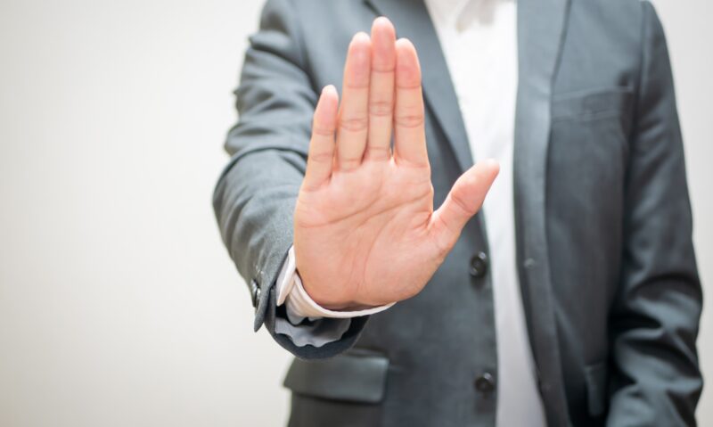 お断りのジェスチャーサインをするビジネスマン