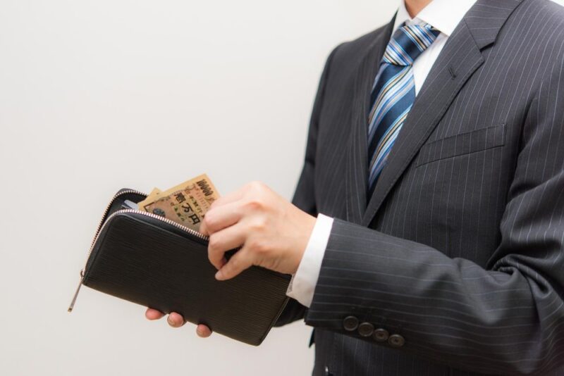 スーツ姿で財布を手にする男性(料金のイメージ)