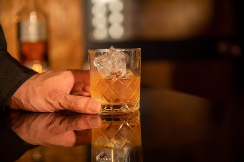 氷を入れた琥珀色のお酒のグラスを持つ手元
