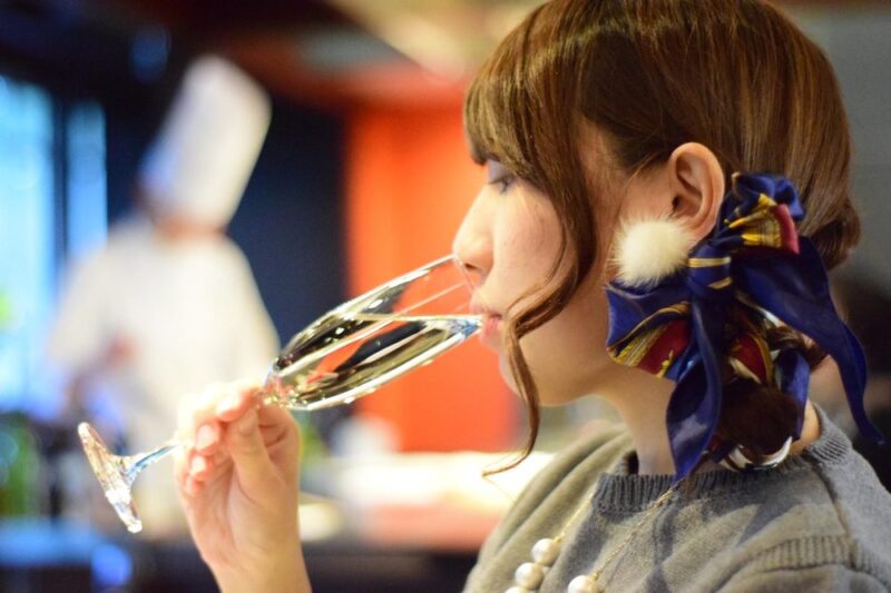 髪飾りをつけた女性がシャンパングラスを傾けて味わう横顔
