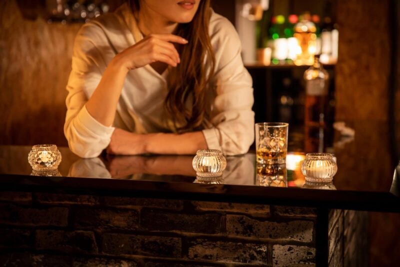 キャンドルの灯る店内のカウンターでお酒を楽しむ女性