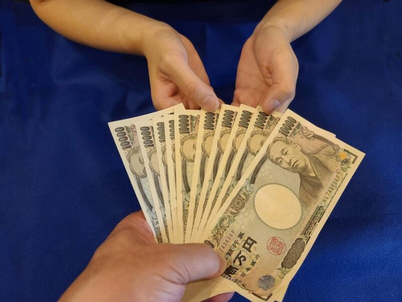 複数の一万円札を扇状に広げて持つ手(費用や予算のイメージ)