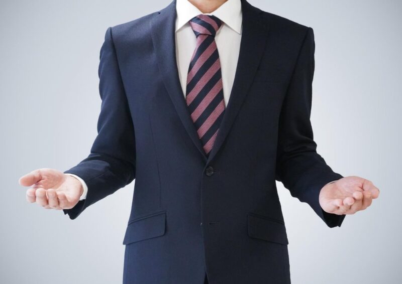 両手を広げるスーツ姿の男性